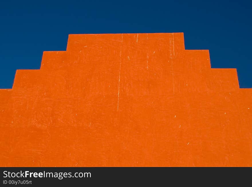 Symmetrical orange stepped structure against blue sky. Symmetrical orange stepped structure against blue sky