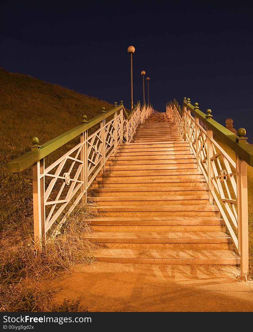 The shined stairs with street lanterns conducts on a hill, above which the dark blue sky. The shined stairs with street lanterns conducts on a hill, above which the dark blue sky.