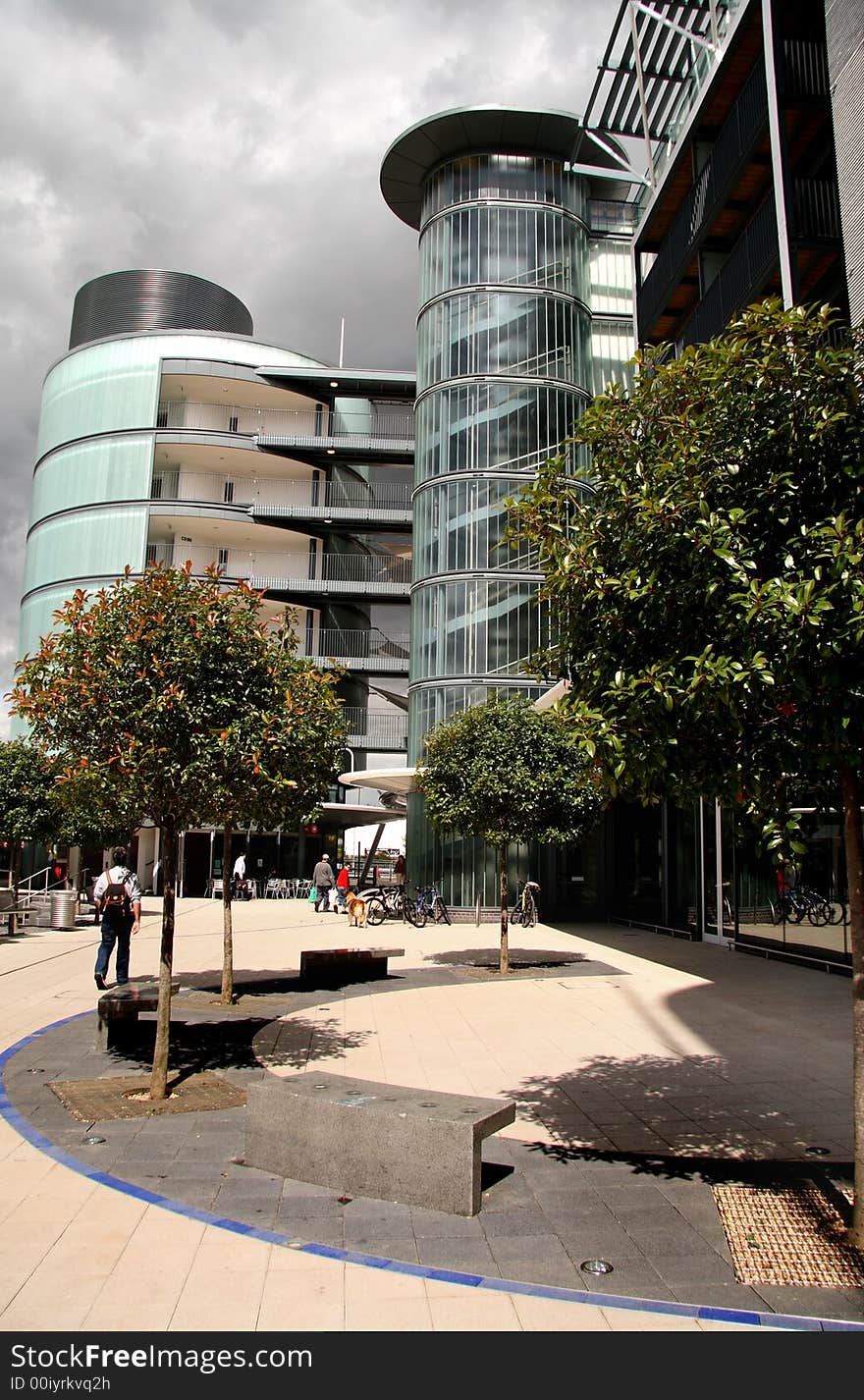 Shop and Apartment block with threatening stormy clouds above and people walking about. Shop and Apartment block with threatening stormy clouds above and people walking about