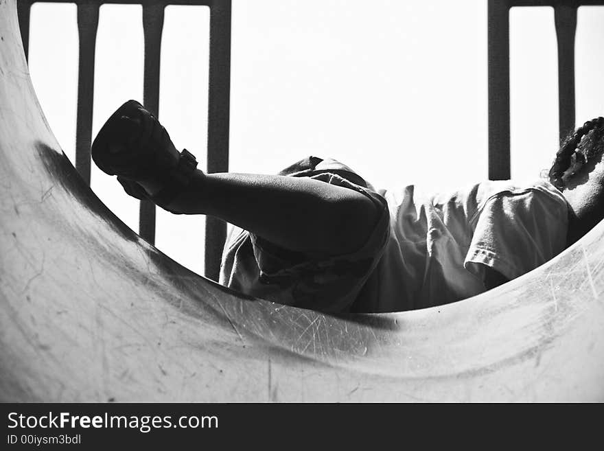 Toddler getting himself positioned to go down through the barrel of a slide. Toddler getting himself positioned to go down through the barrel of a slide