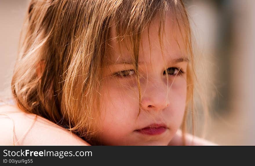 Face-only portrait of a serious young girl with hair wet from swimming, laying in the sun. Face-only portrait of a serious young girl with hair wet from swimming, laying in the sun.