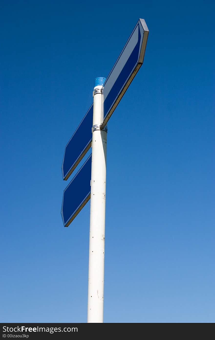 Empty road sign, two directions, isolated against a clear blue sky. Empty road sign, two directions, isolated against a clear blue sky