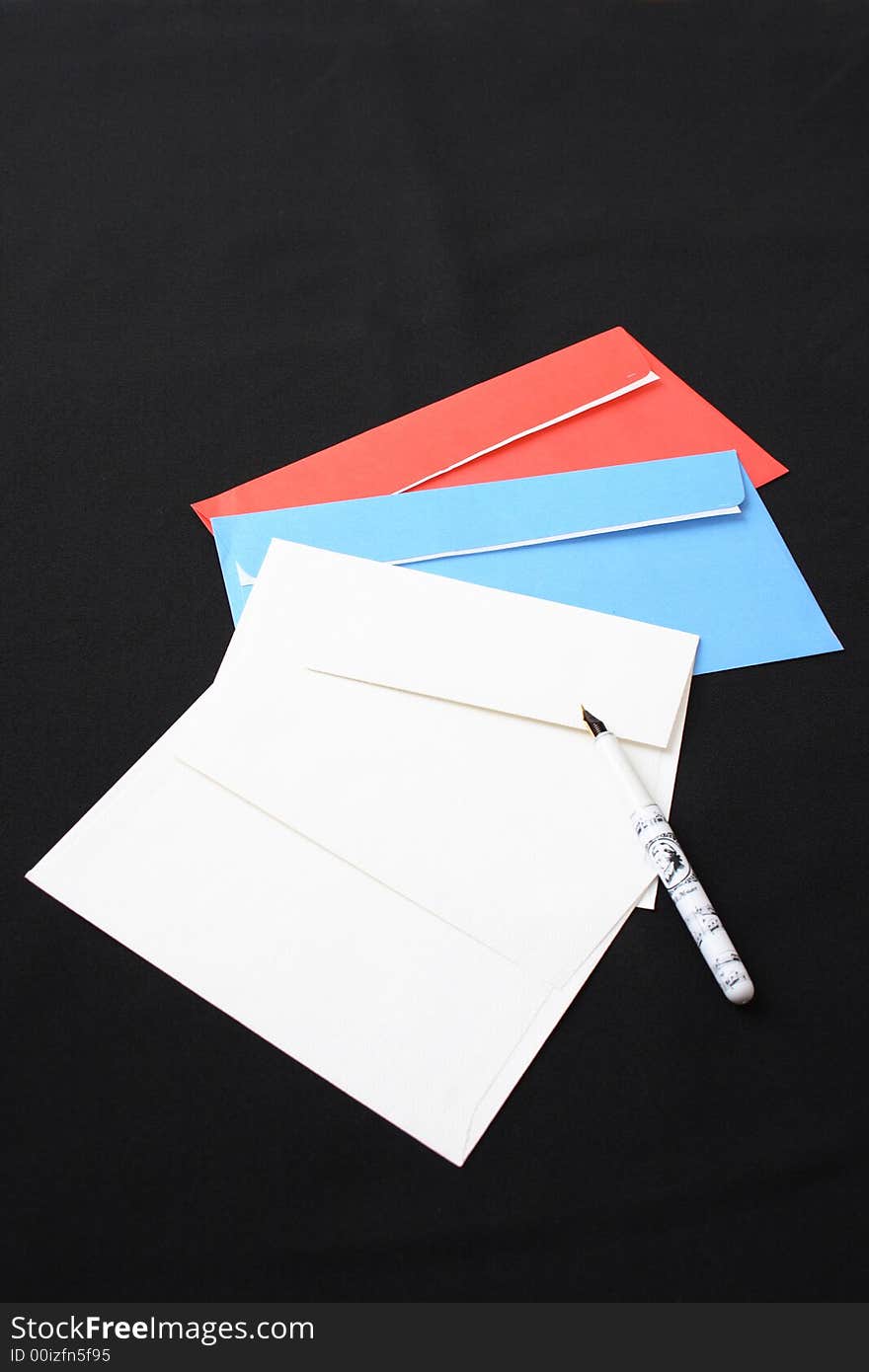 Multi-coloured envelopes and the pen on a black background