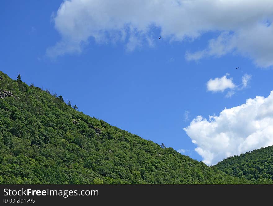 Green mountain slope and the blue sky with clouds.