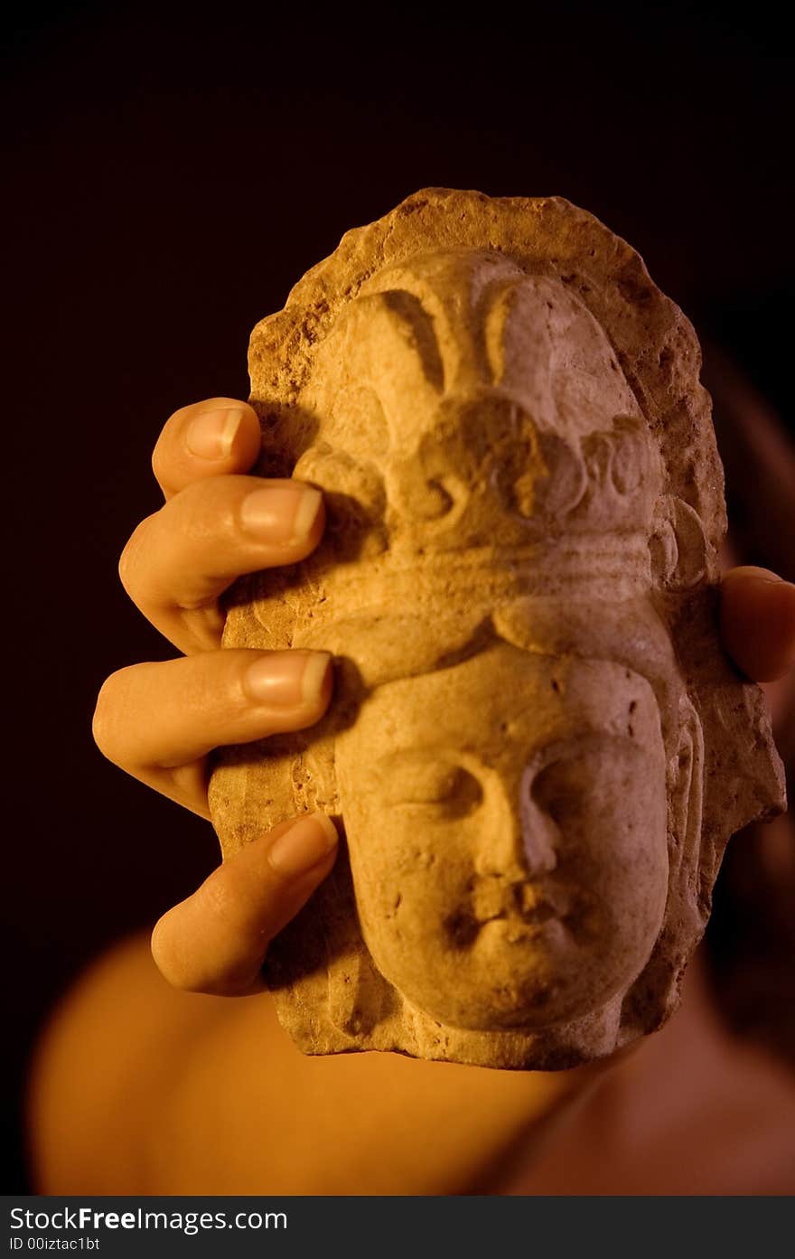 Close up of hand holding a stone buddha statue over black background. Close up of hand holding a stone buddha statue over black background