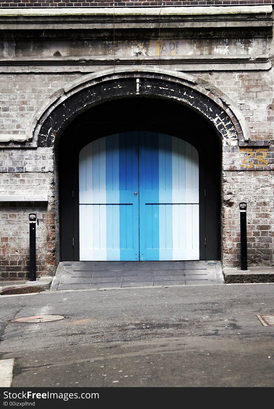 Colourful Blue Door In An Old Brick Wall, Backstreet Entrance, Background. Colourful Blue Door In An Old Brick Wall, Backstreet Entrance, Background