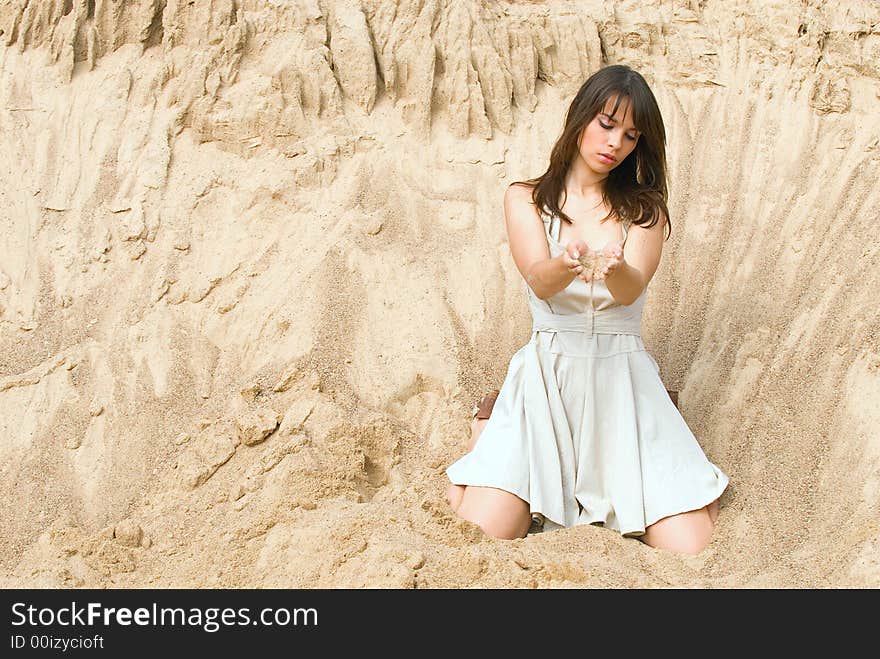 The girl sits among sand and reflects. The girl sits among sand and reflects