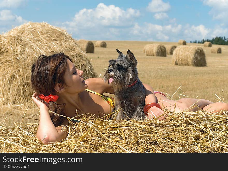 The girl lays on a haystack with dog. The girl lays on a haystack with dog