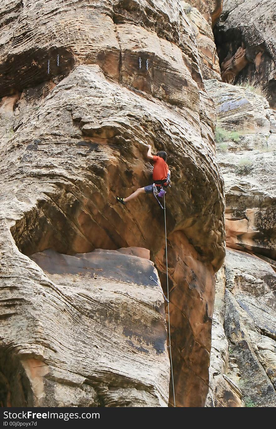 A rock climber works his way over an overhang. He is hanging onto the nose of the problem. A rock climber works his way over an overhang. He is hanging onto the nose of the problem.