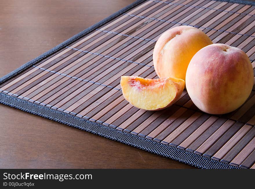 Two juicy peaches on a bamboo napkin. Two juicy peaches on a bamboo napkin