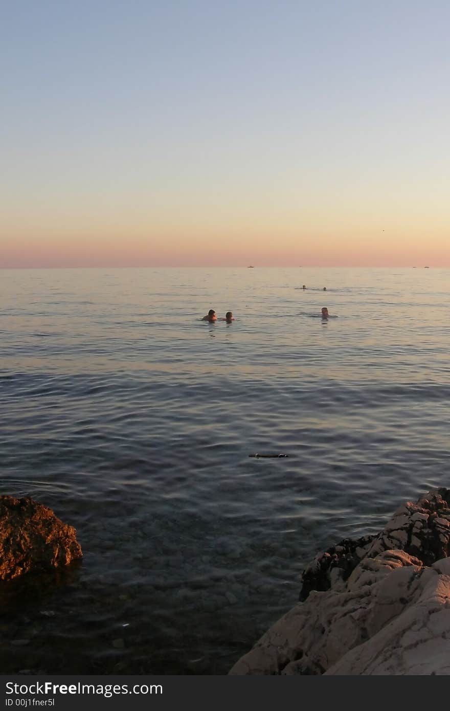 Family having a swim at sunset, grandmother, father and daughter swimming at dusk in the sea. Family having a swim at sunset, grandmother, father and daughter swimming at dusk in the sea