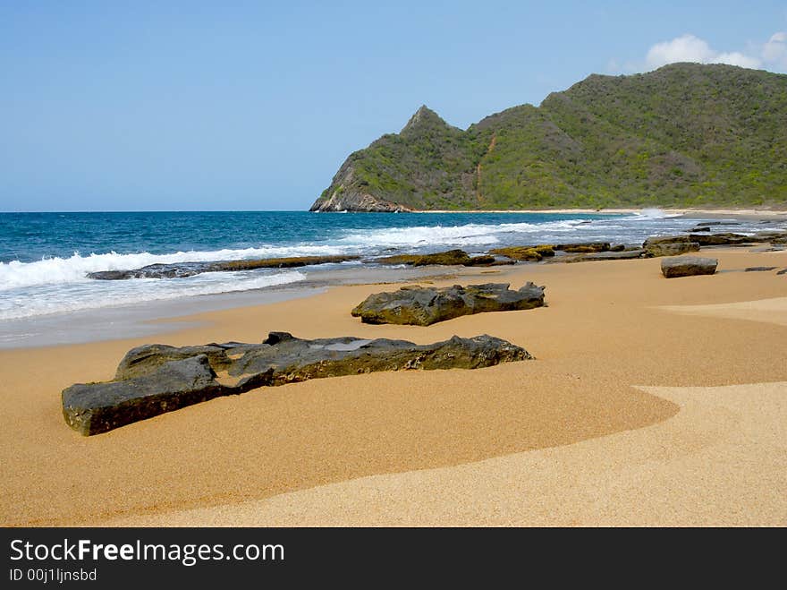 Whitewash on tropical caribbean island with hill on the horizon and rocks on the beach. Whitewash on tropical caribbean island with hill on the horizon and rocks on the beach