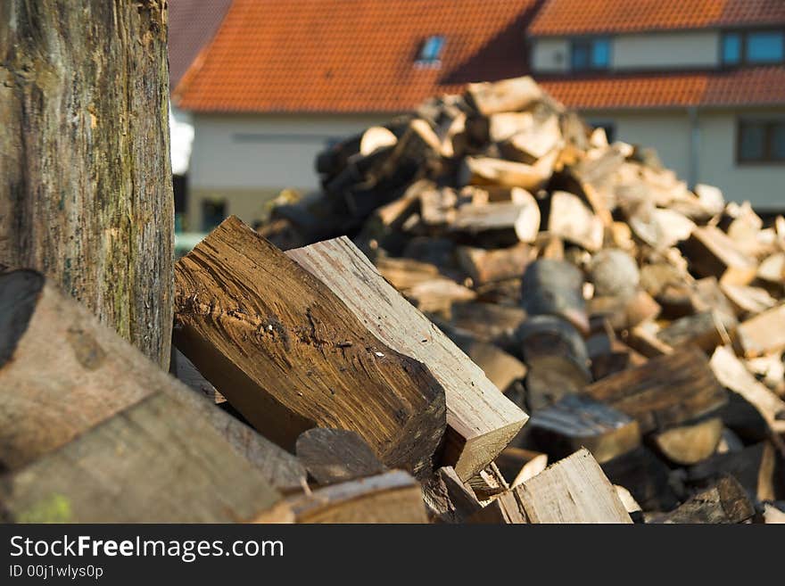 Pile of split fire wood with a house in the background. Pile of split fire wood with a house in the background.