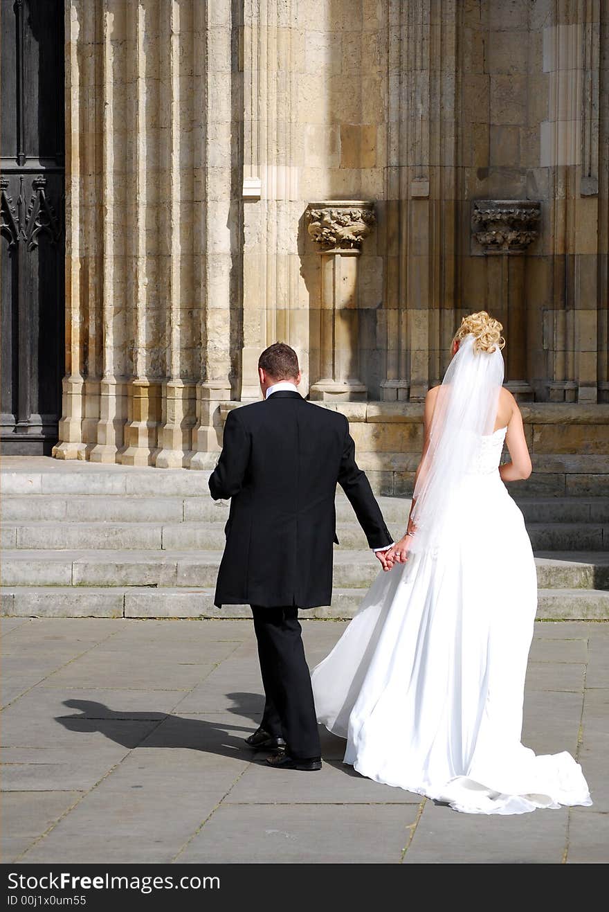 Bride and groom walking towards church. Bride and groom walking towards church