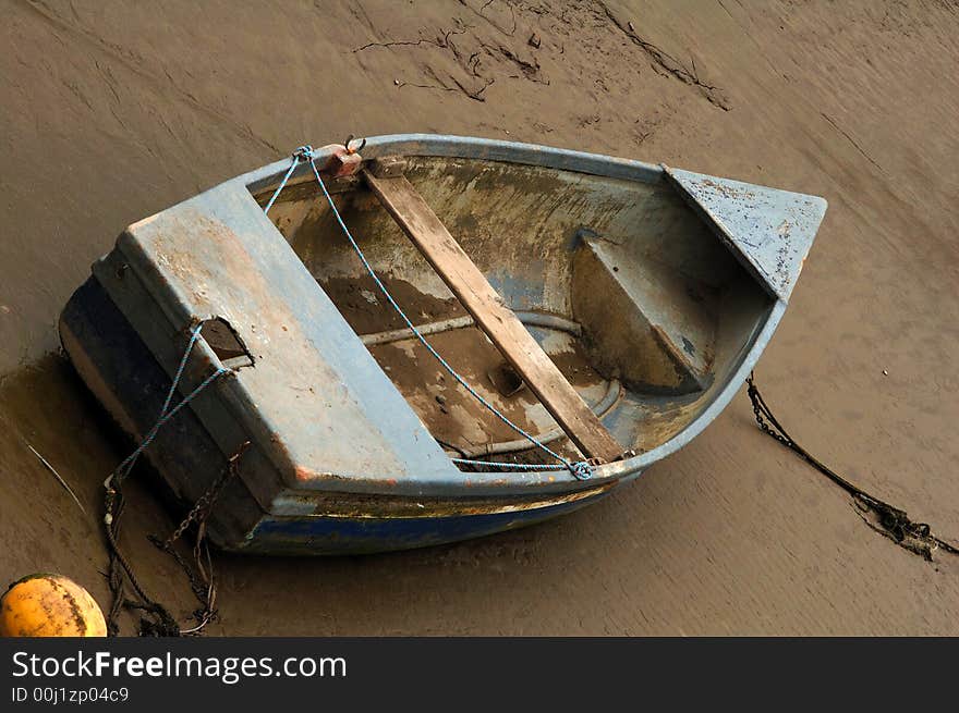 Old and weathered rowing boat tied up and beached on the sand. Old and weathered rowing boat tied up and beached on the sand