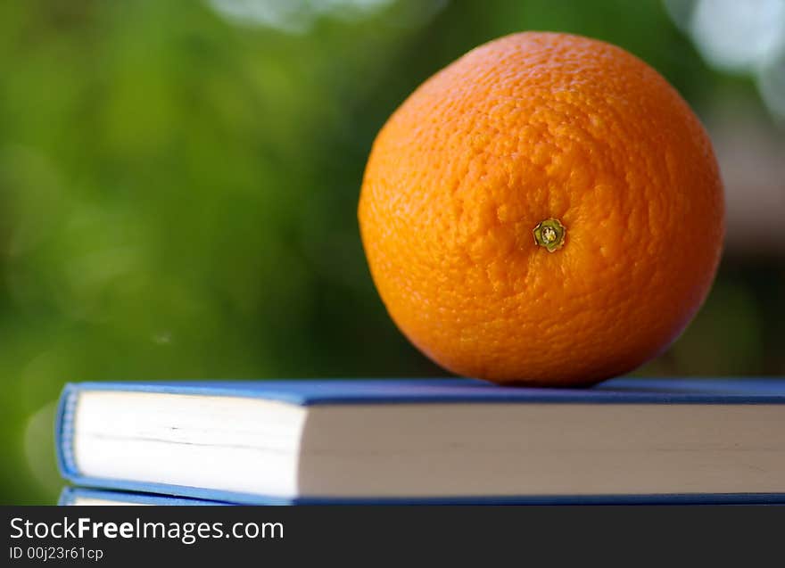 An orange on a book of the blue color.