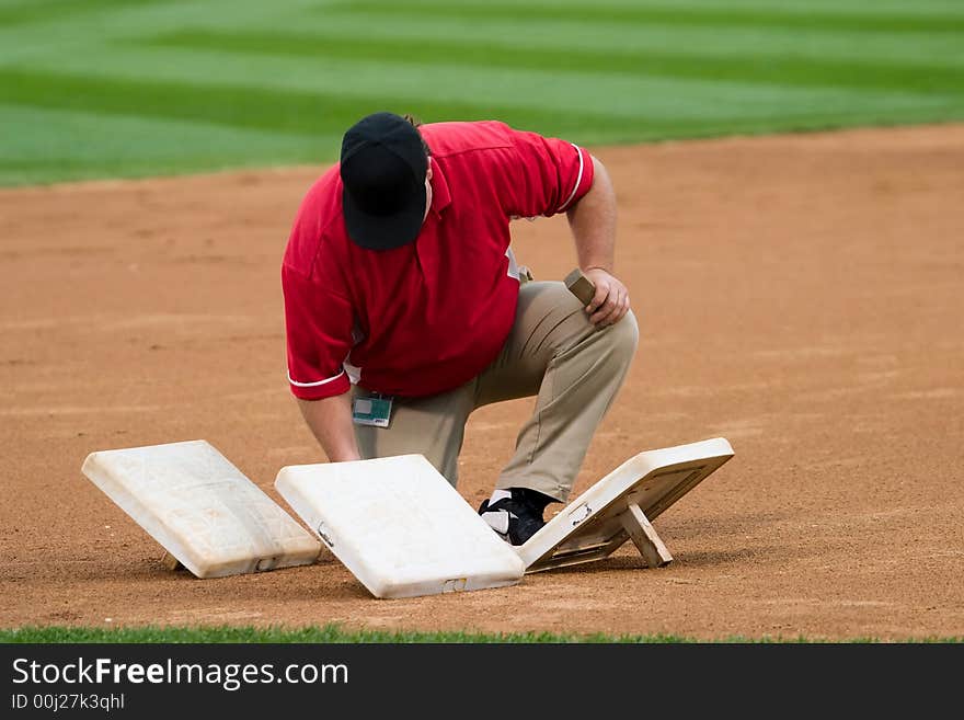 A man prepares third base before a baseball game. A man prepares third base before a baseball game.