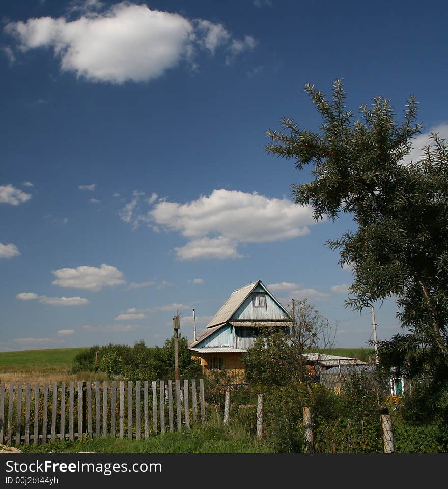 The village house and the green field landscape and blue sky with clouds as a background.