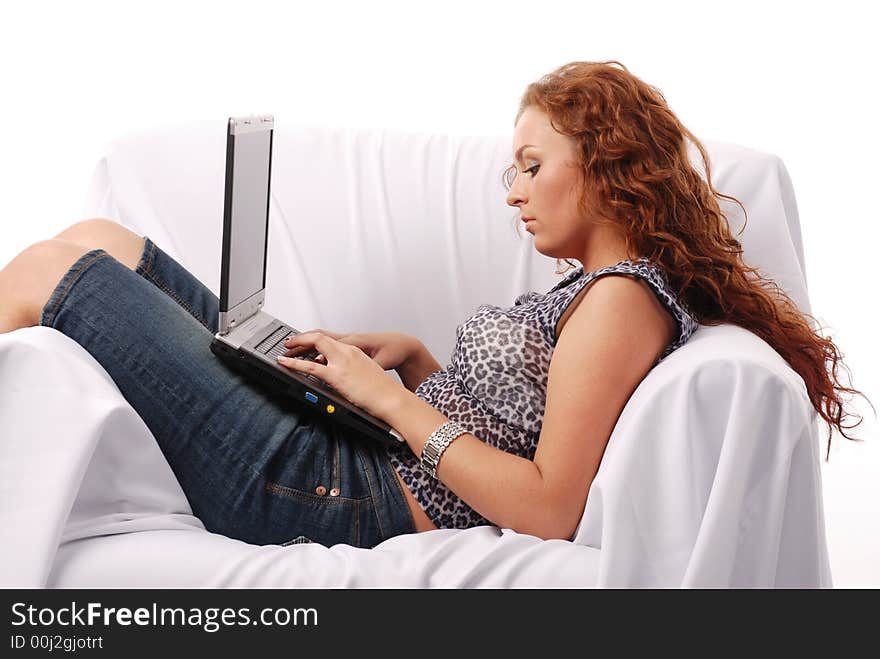 Red hair beautyful young girl using laptop on a sofa covered by white sheet. Red hair beautyful young girl using laptop on a sofa covered by white sheet.