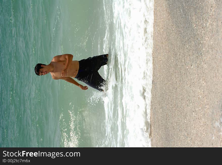 An attractive, smiling, fit teenager playing in the surf. An attractive, smiling, fit teenager playing in the surf.