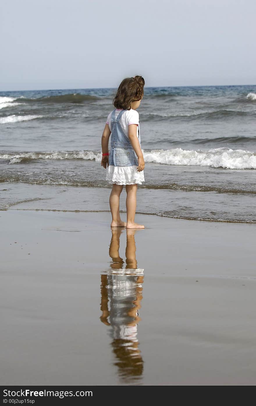 Child is standing on the beach looking at the sea. Child is standing on the beach looking at the sea.