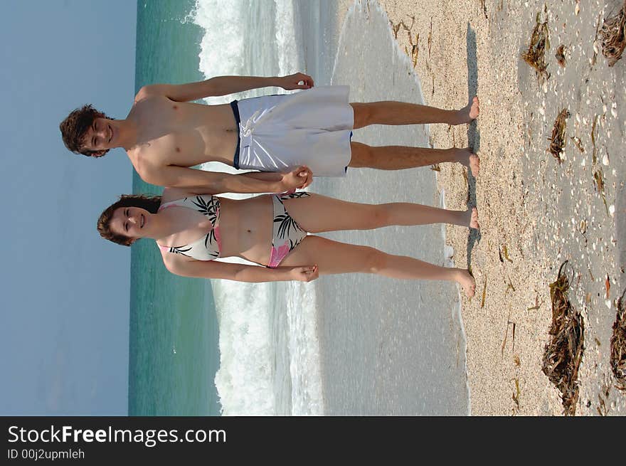 A young couple in swim suits holding hands on the beach. A young couple in swim suits holding hands on the beach