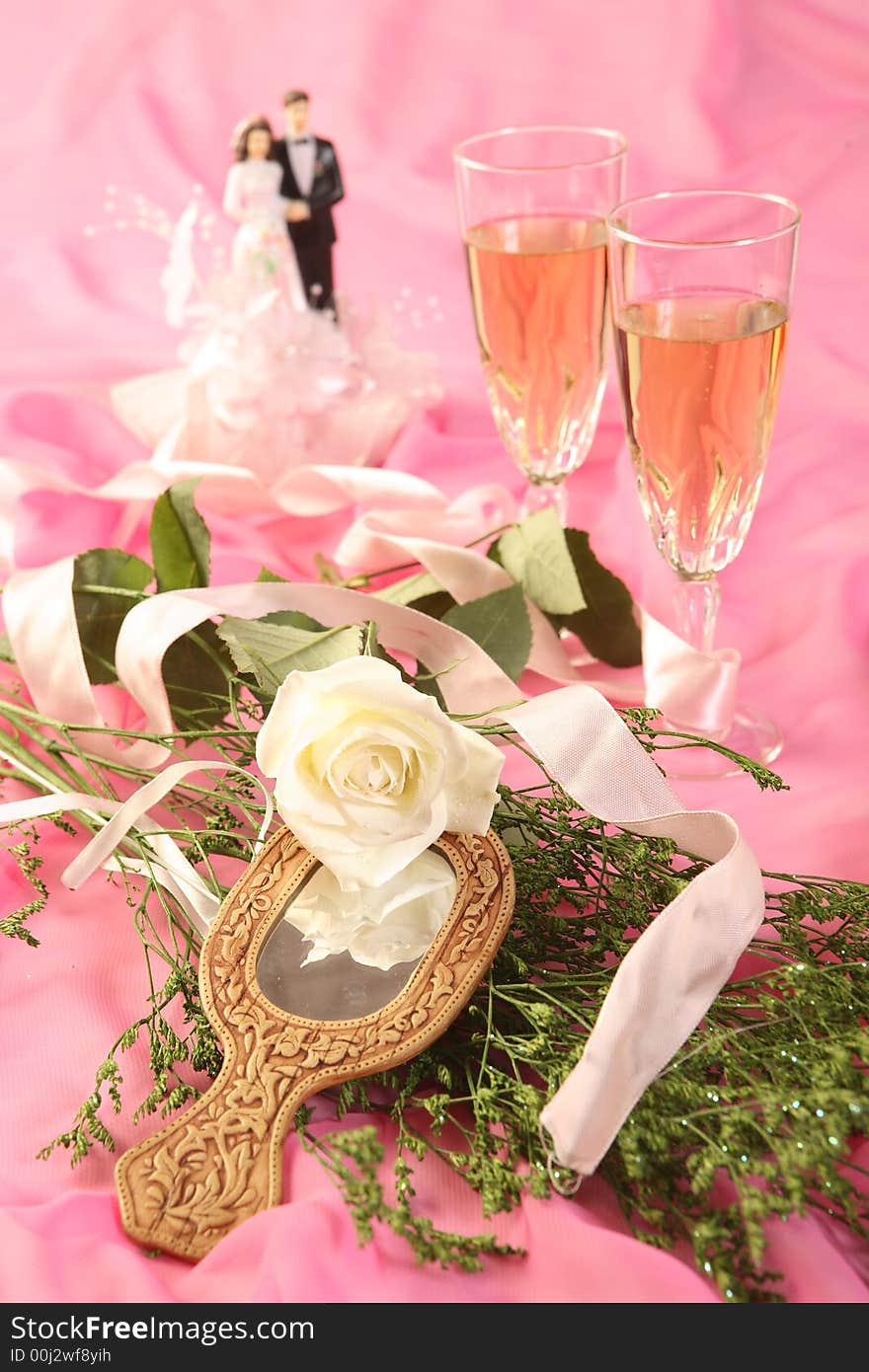 A photo of wedding cake dolls, rose and glasses over pink