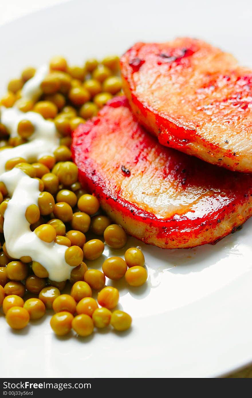 Roasted pork and green peas on white plate