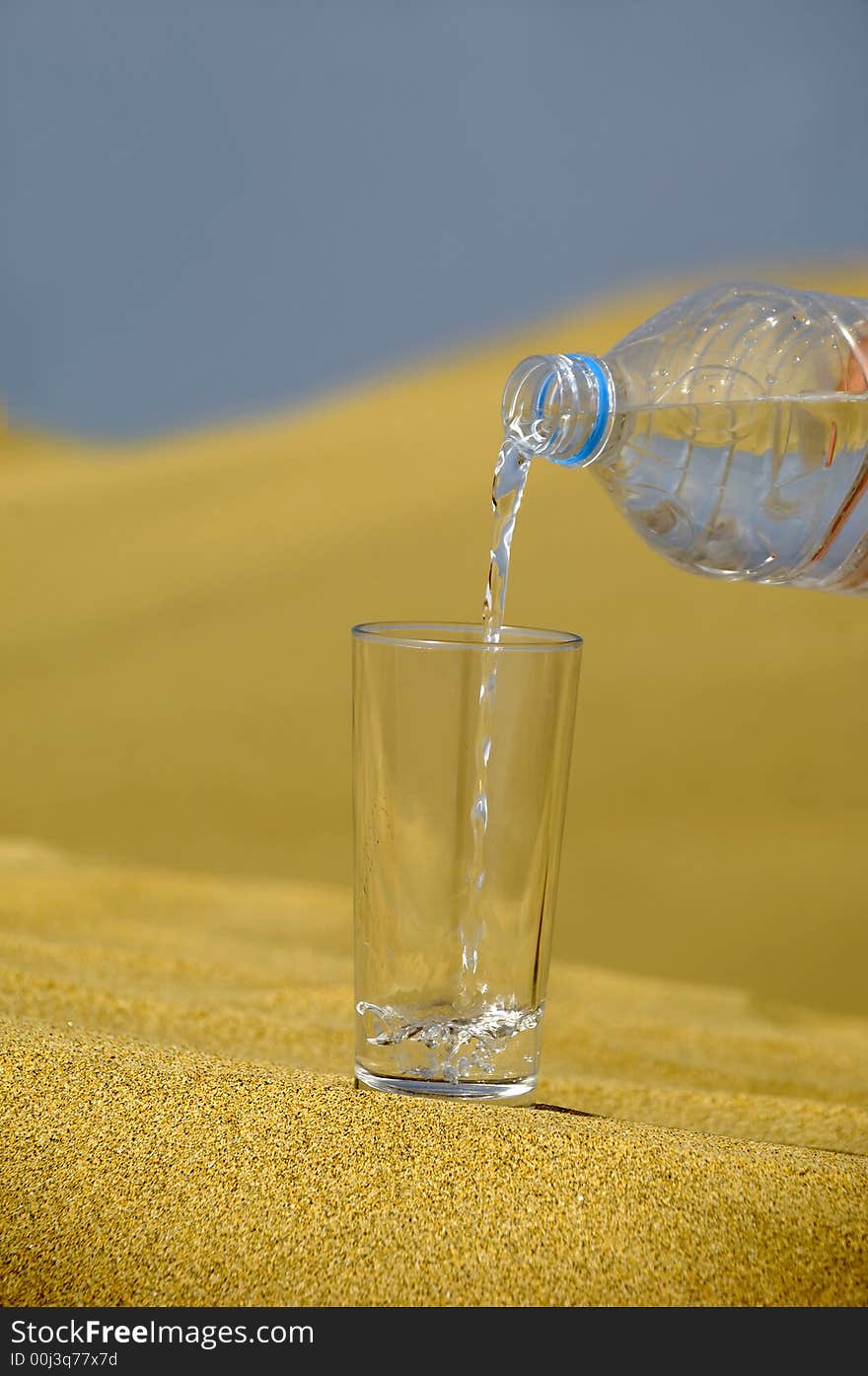 A glass of fresh water and bottle in a desert. A glass of fresh water and bottle in a desert