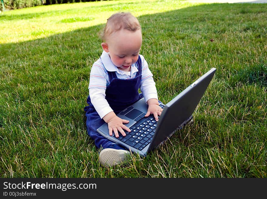 Baby study on computer on lawn