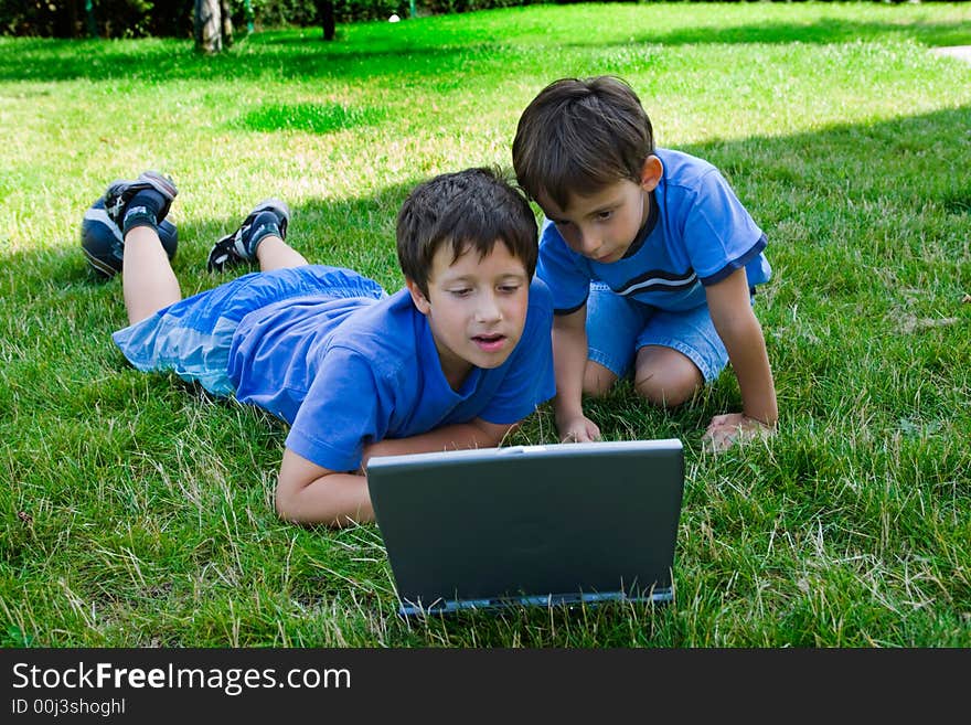 Two cute boy study on computer in courtyard