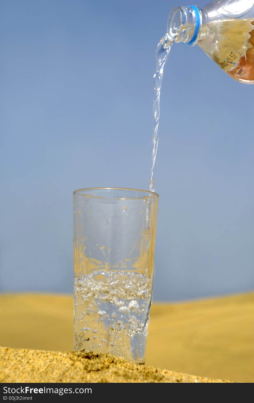 A glass of fresh water and bottle in a desert. A glass of fresh water and bottle in a desert