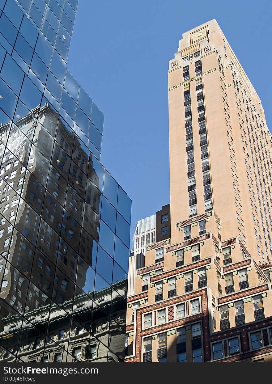 A composition of old and new buildings in New York City against a blue sky. A composition of old and new buildings in New York City against a blue sky.