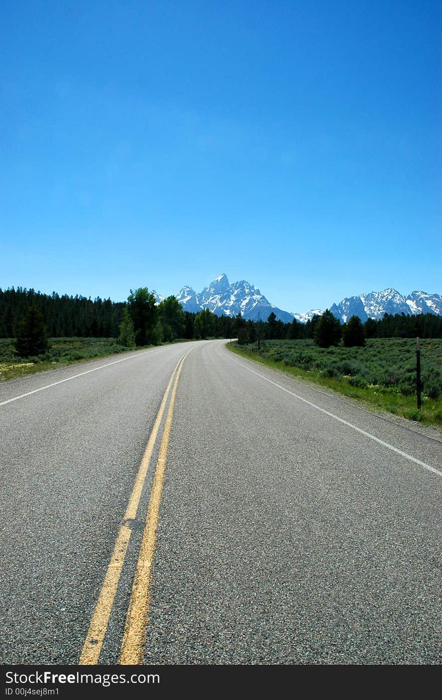 A blacktop highway running into the mountains of Yellowstone National Park. A blacktop highway running into the mountains of Yellowstone National Park.