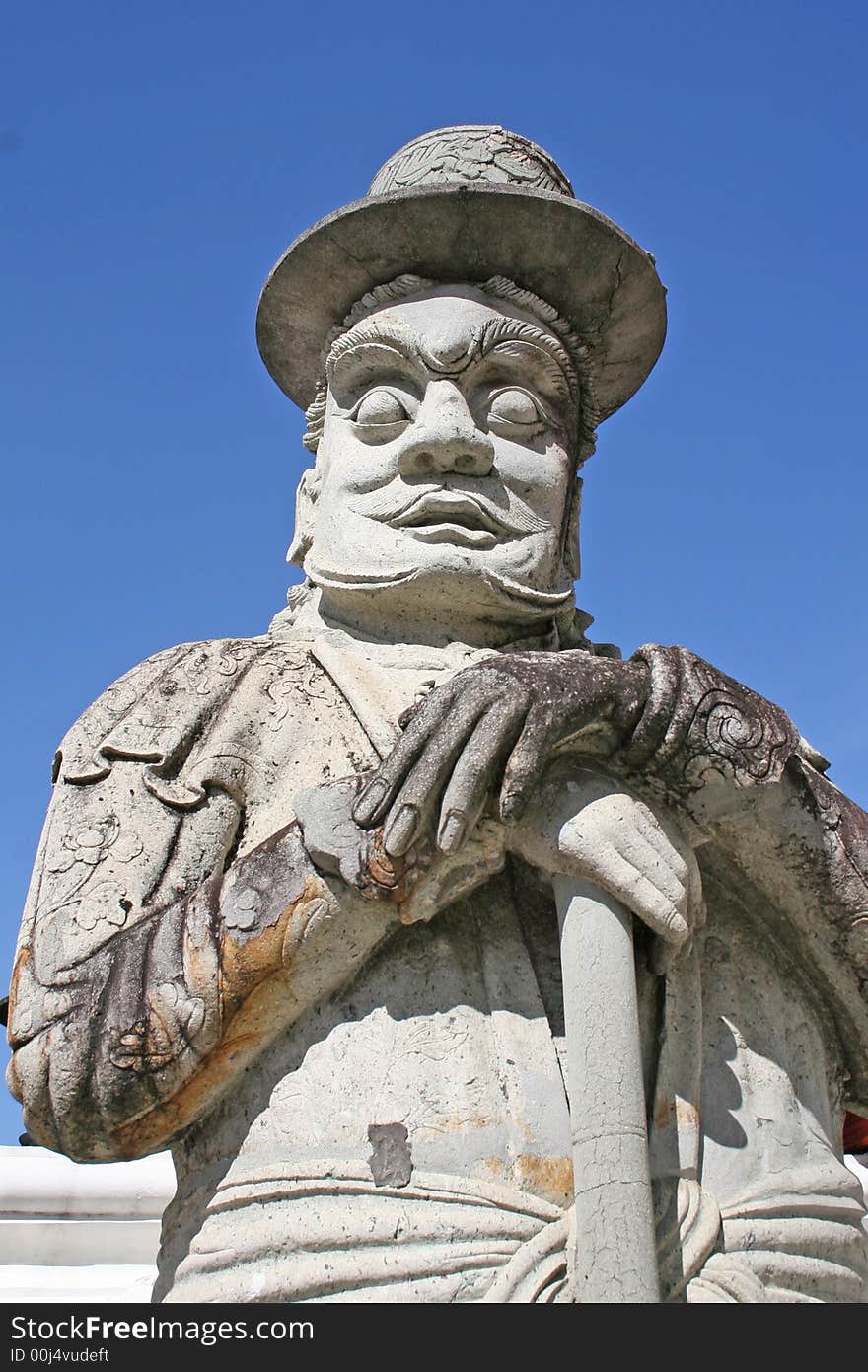 A stone statue stands guard outside of the Grand Palace in Bangkok