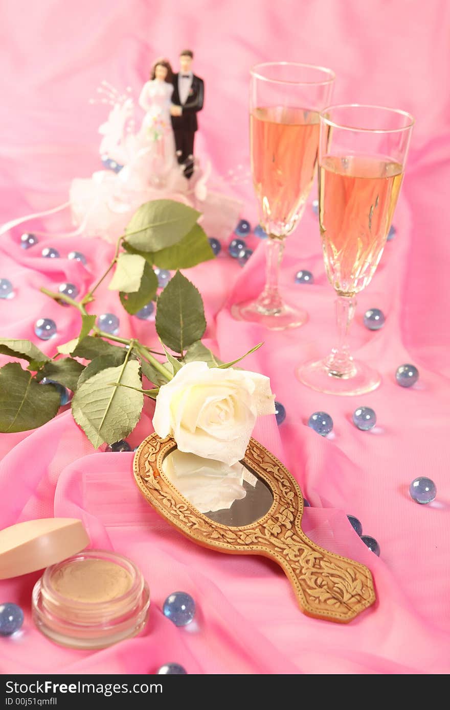 A photo of wedding cake dolls, rose and glasses over pink