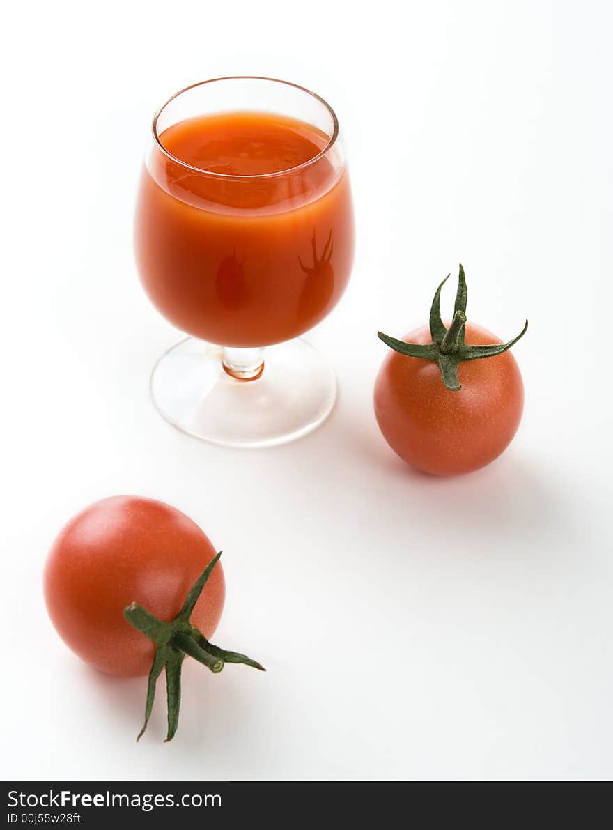 Tomatoes and tomato juice in a glass on a white background