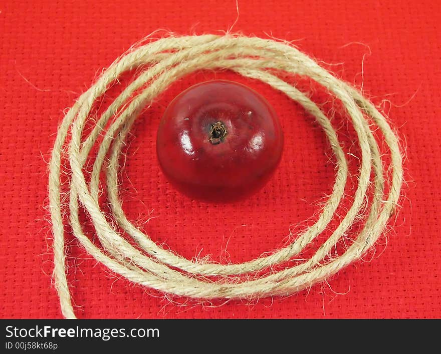 Nature, composition: red apple and string on red tissue