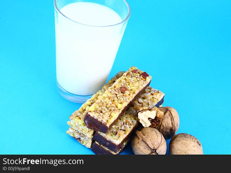 Pouring white milk against blue background and glass