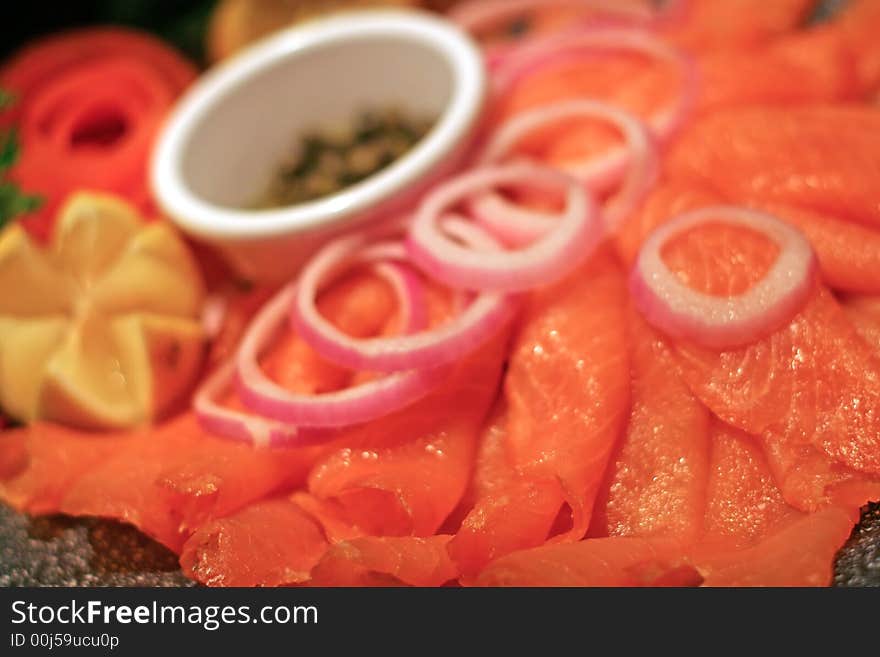 A deli tray of smoked salmon with lemon onions and capers. A deli tray of smoked salmon with lemon onions and capers