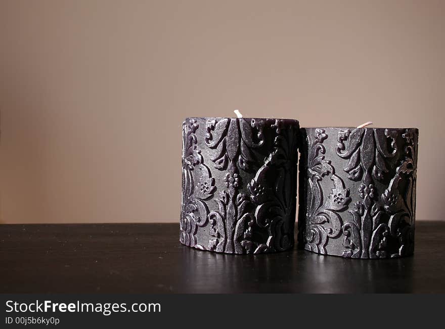 Two candles on a brown wooden surface