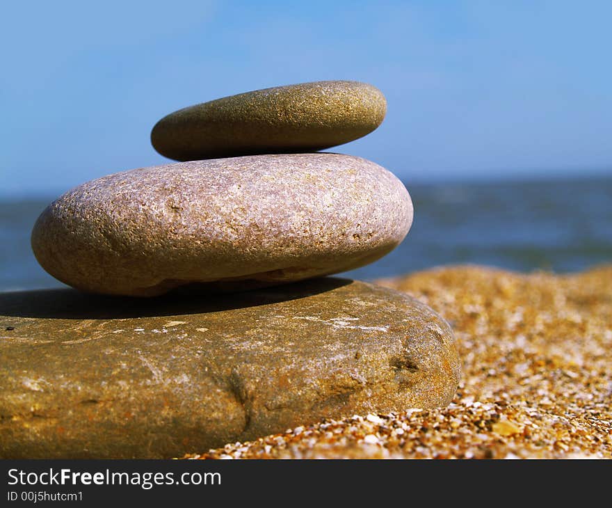 Warm stone on the beach on blue sky background