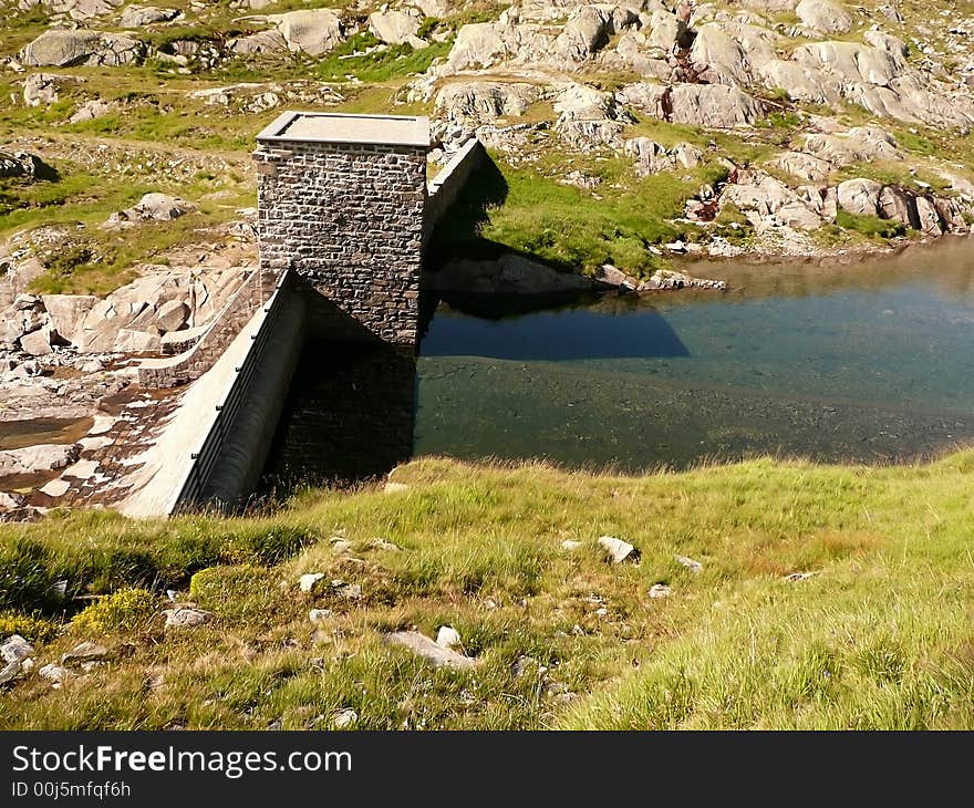 Little dam with a tower. The water reflection is beautiful! There are three kind of reflection (the sky, the tower and a ridge of a mountain) and there is also trasparency (we can see the lakebed). Little dam with a tower. The water reflection is beautiful! There are three kind of reflection (the sky, the tower and a ridge of a mountain) and there is also trasparency (we can see the lakebed).