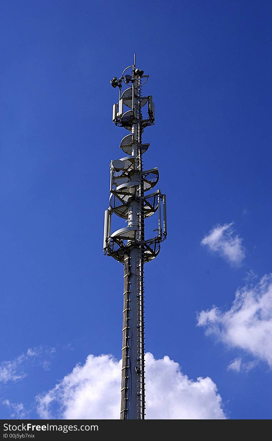 Cell phone antenna pillar in sunny day with white clouds