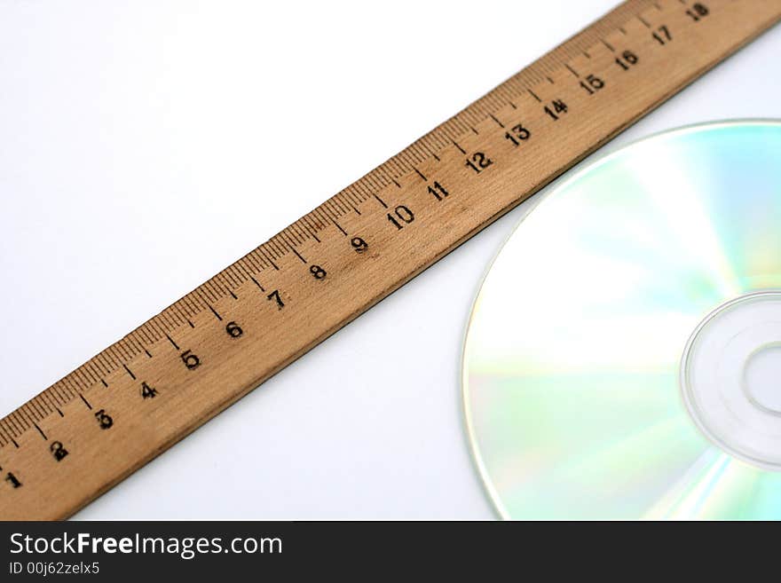 A wooden ruler laying near the cd disc. A wooden ruler laying near the cd disc