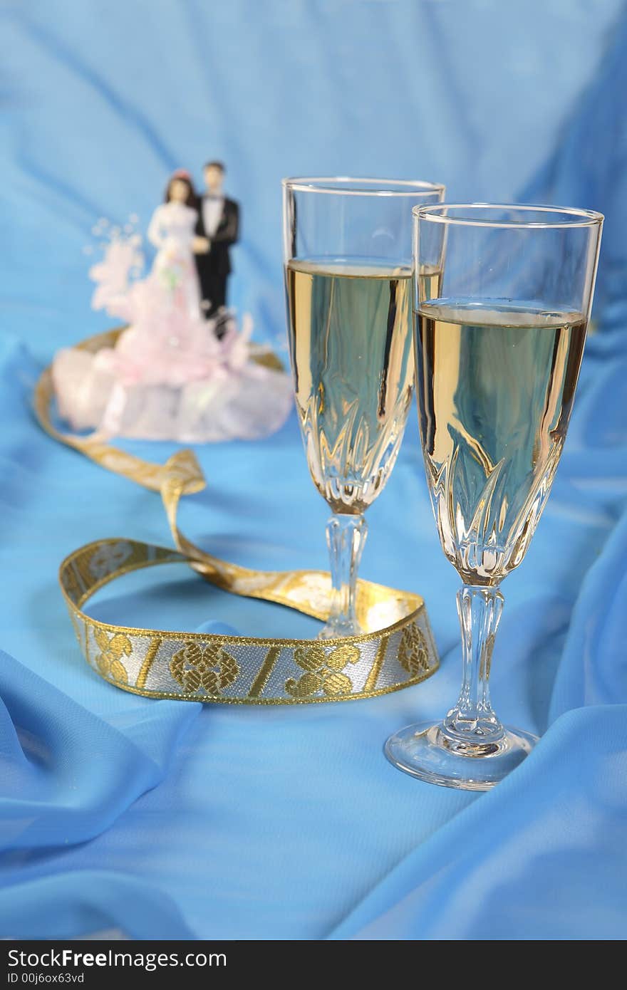 A photo of wedding cake dolls and glasses over blue. A photo of wedding cake dolls and glasses over blue