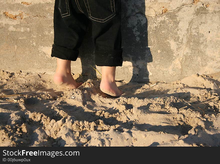 A child's feet on the beach standing halfway on his toes. A child's feet on the beach standing halfway on his toes