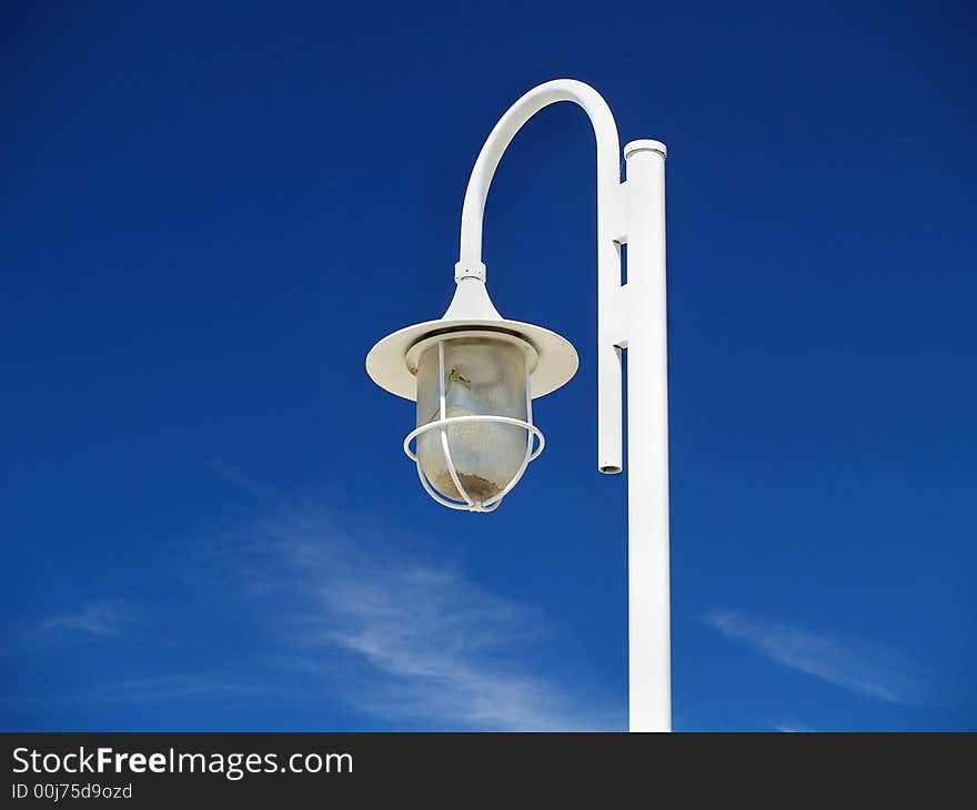 A white street lamp against a blue sky. A white street lamp against a blue sky.