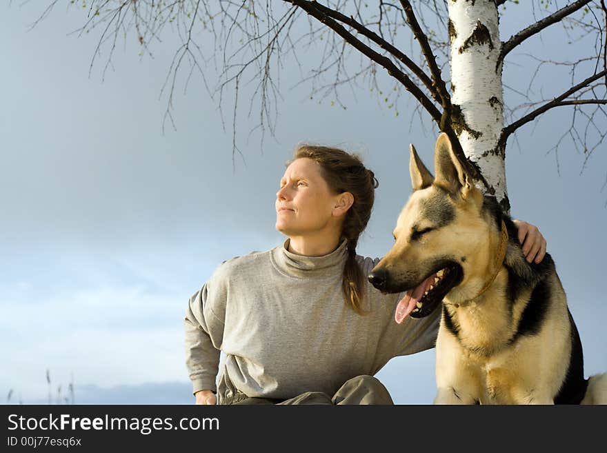 Woman with alsatian dog under birch at sunset. Woman with alsatian dog under birch at sunset