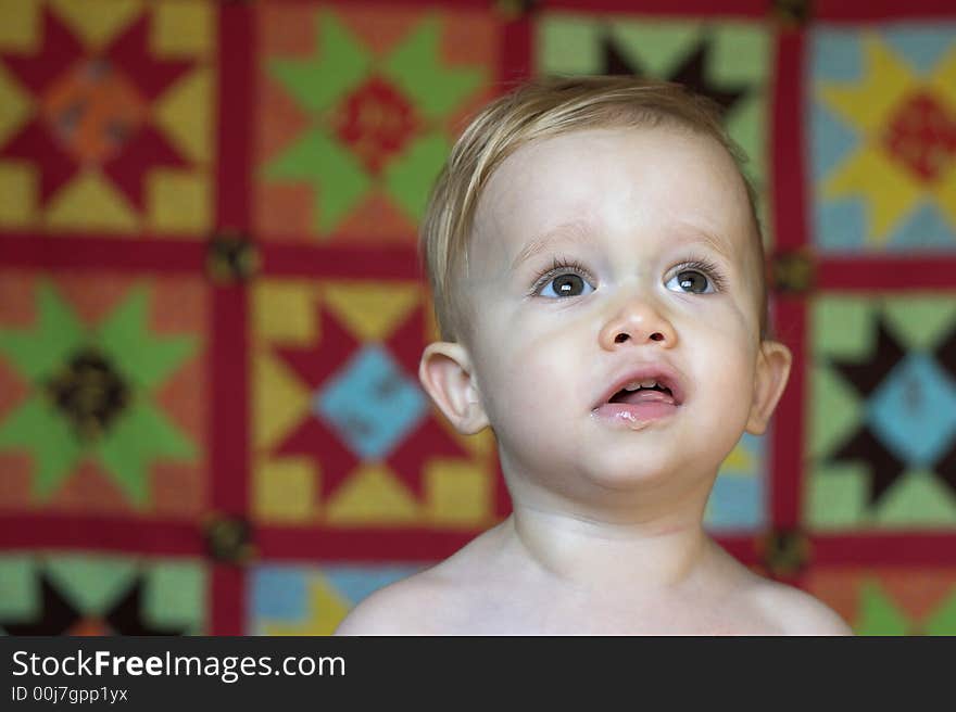 Image of cute toddler with a quilt in the background